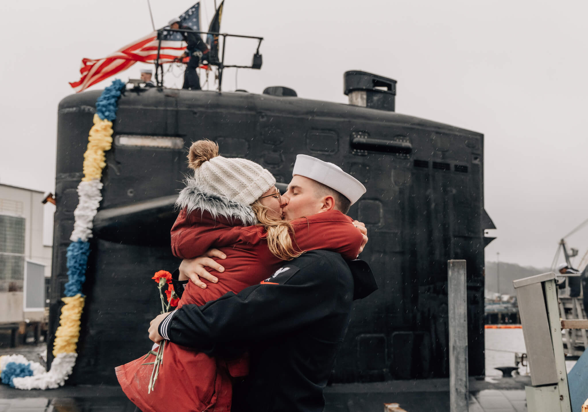 Sailor embraces significant other in front of USS Newport News at homecoming at SUBASE New London in Groton, CT on January 3, 2023.