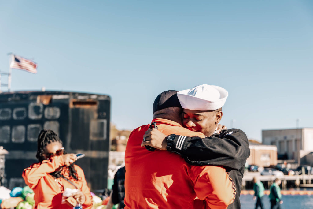 Sailor embraces family member at military homecoming from USS North Dakota.