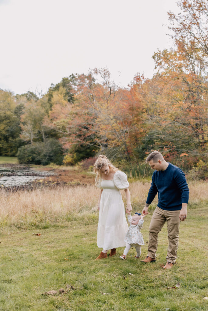 Family walking and holding hands at Ledyard Sawmill with fall foliage.